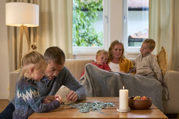 alt-Text: Familie im Wohnzimmer auf Couch am Puzzeln