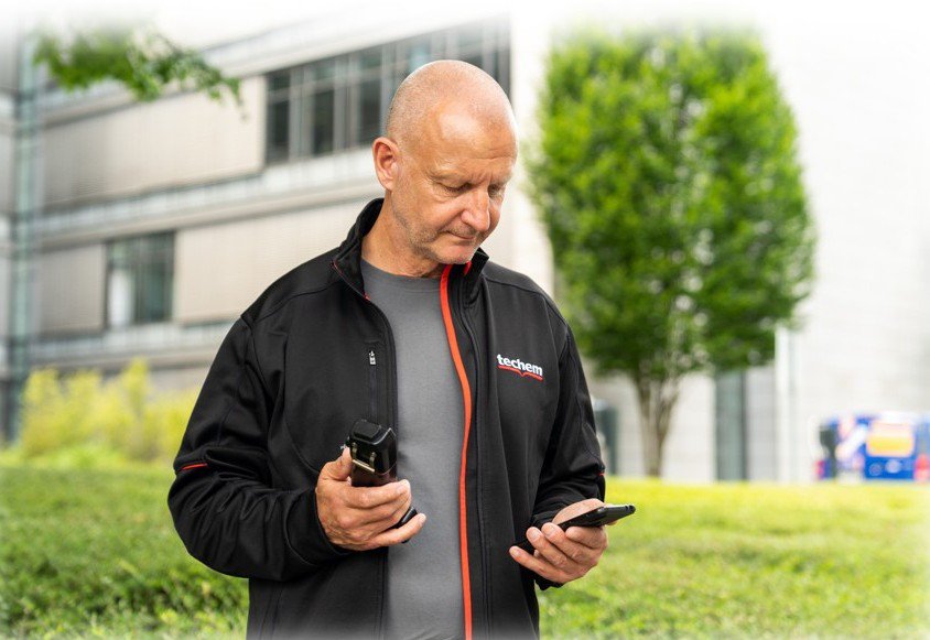 Techem Ableser mit einem Smartphone in der Hand