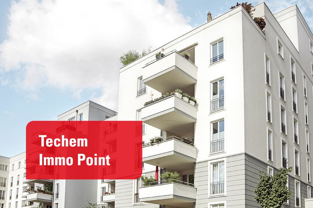 Mehrstöckige, moderne Wohnhäuser mit Balkonen.  Links unten steht „Techem Immo Point“ auf einem roten Feld.