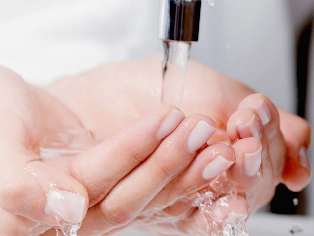 Zwei Hände unter laufendem Wasserstrahl