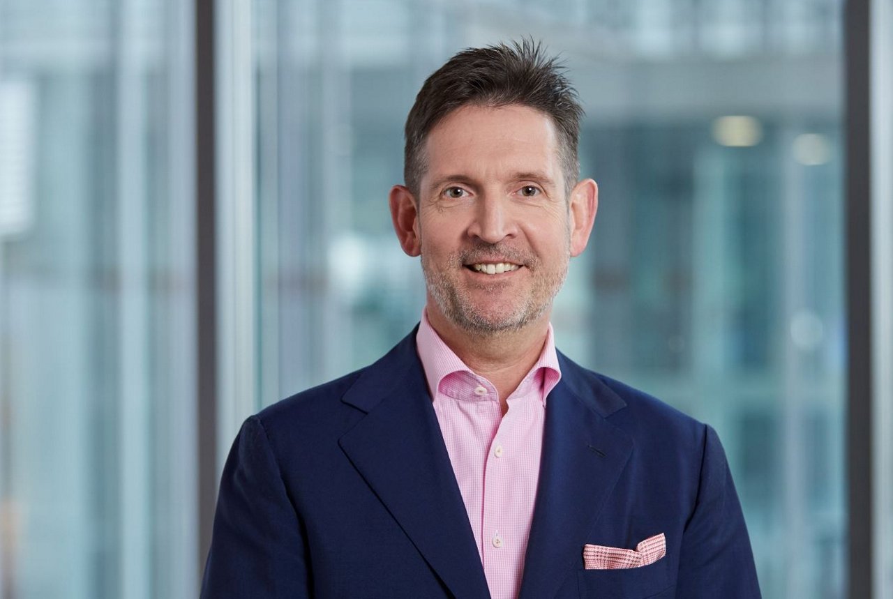 alt-Text: Profilbild von Carsten Sürig vor Glaswand