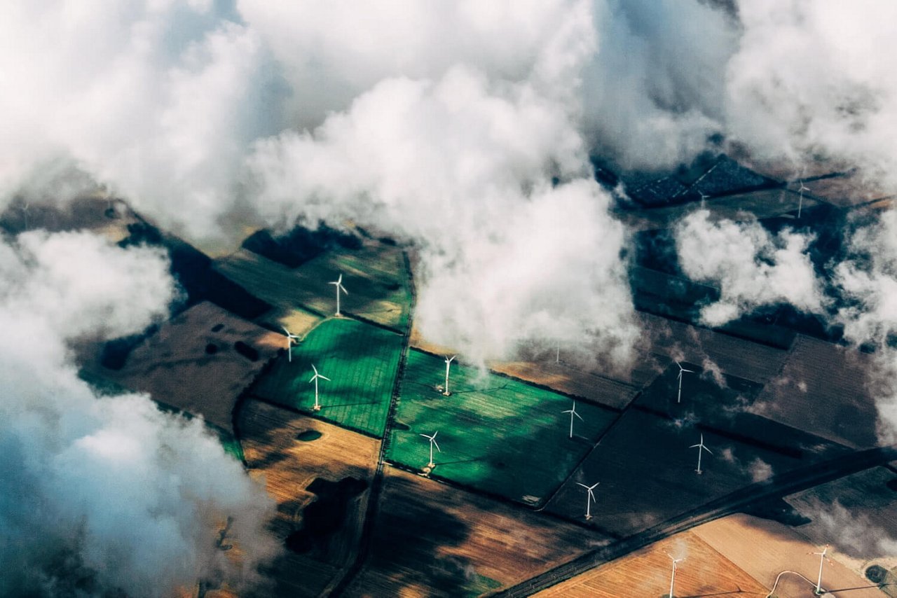 WKA auf landwirtschaftlichen Feldern stehend von der Luft aus zwischen den Wolken