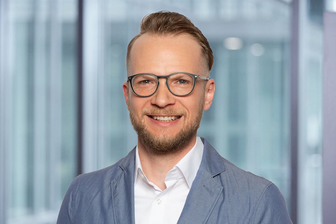 Photo du responsable des relevés et de la facturation S. Fenkl sur un fond de bureau flou.