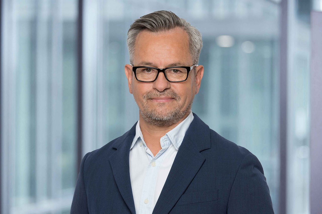 Photo conseiller de vente C. Carrasco de la région Suisse romande devant un arrière-plan de bureau flou.