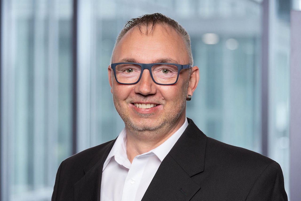 Photo du directeur du service clientèle P. Herzog sur un fond de bureau flou.