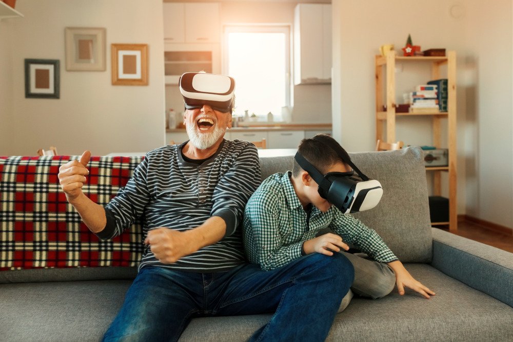 Ein älterer Mann und ein Junge sitzen auf einem Sofa und tragen VR-Brillen