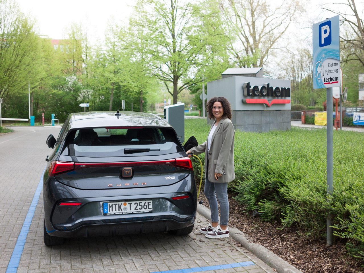 alt-Text: Mitarbeiterin tankt ihr Fahrzeug an Techem EV-Charging Säule
