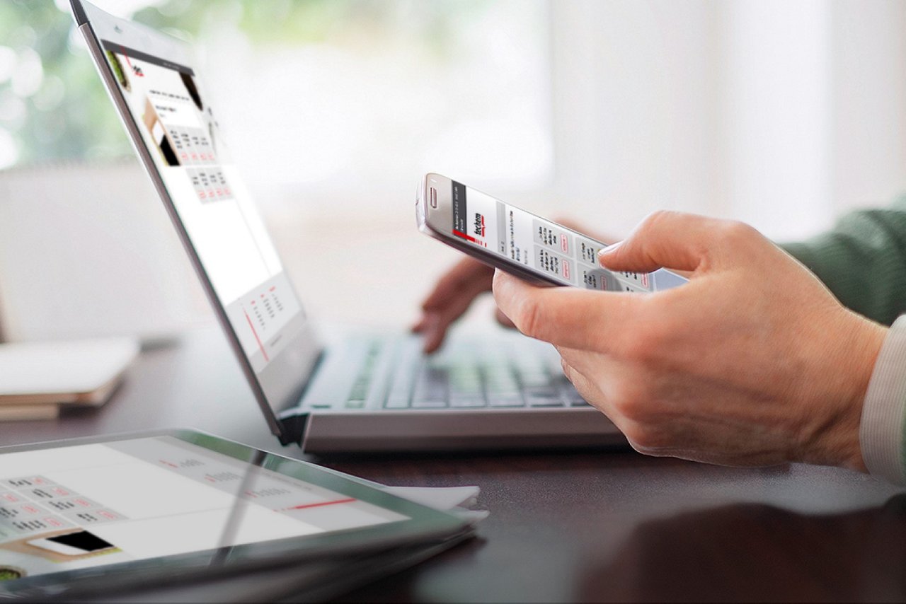 Eine Person arbeitet mit Smartphone, Laptop und Tablet, alle zeigen eine Webseite von Techem.
