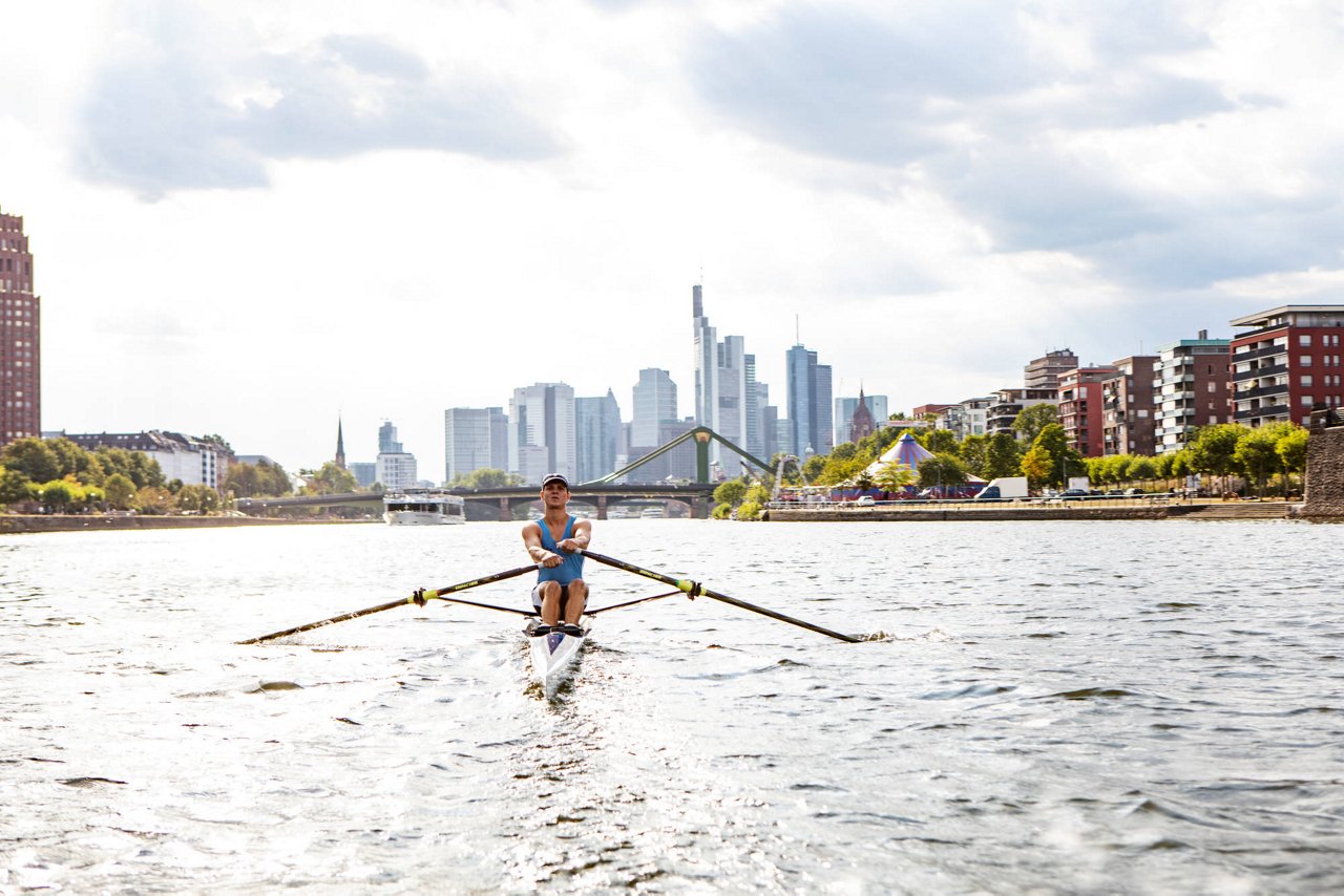 Mann rudert auf Main vor Skyline Frankfurt