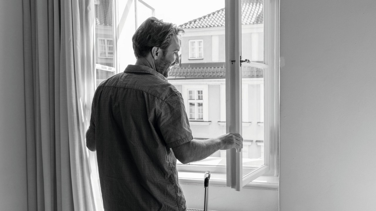 Lächelnder Mann öffnet Fenster
