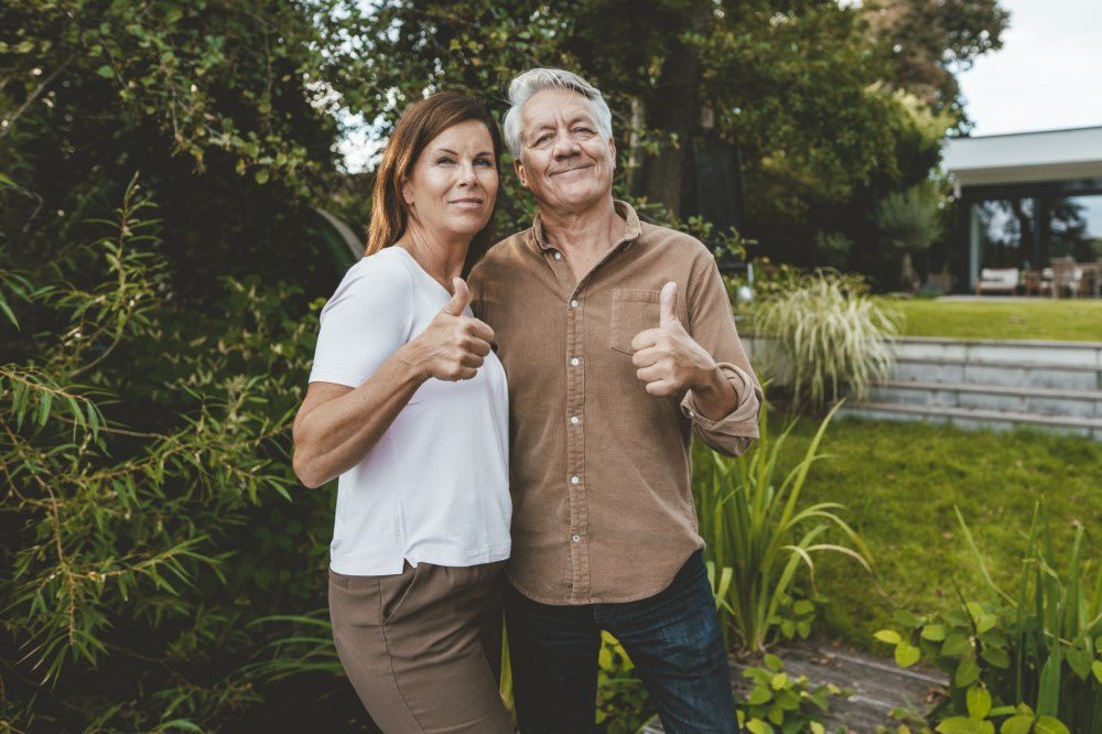 Mann und Frau stehen im Garten mit Daumen hoch 