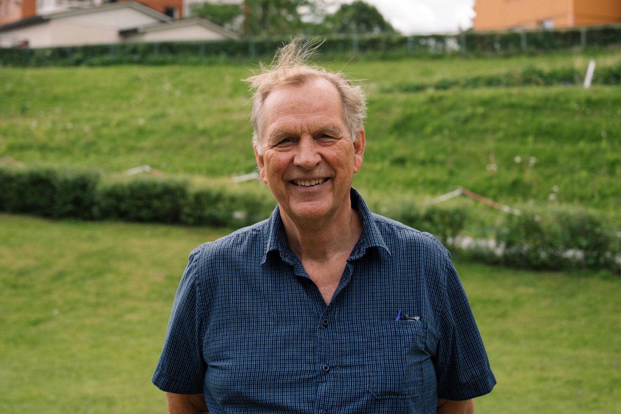 En man står på en gressplen og smiler.