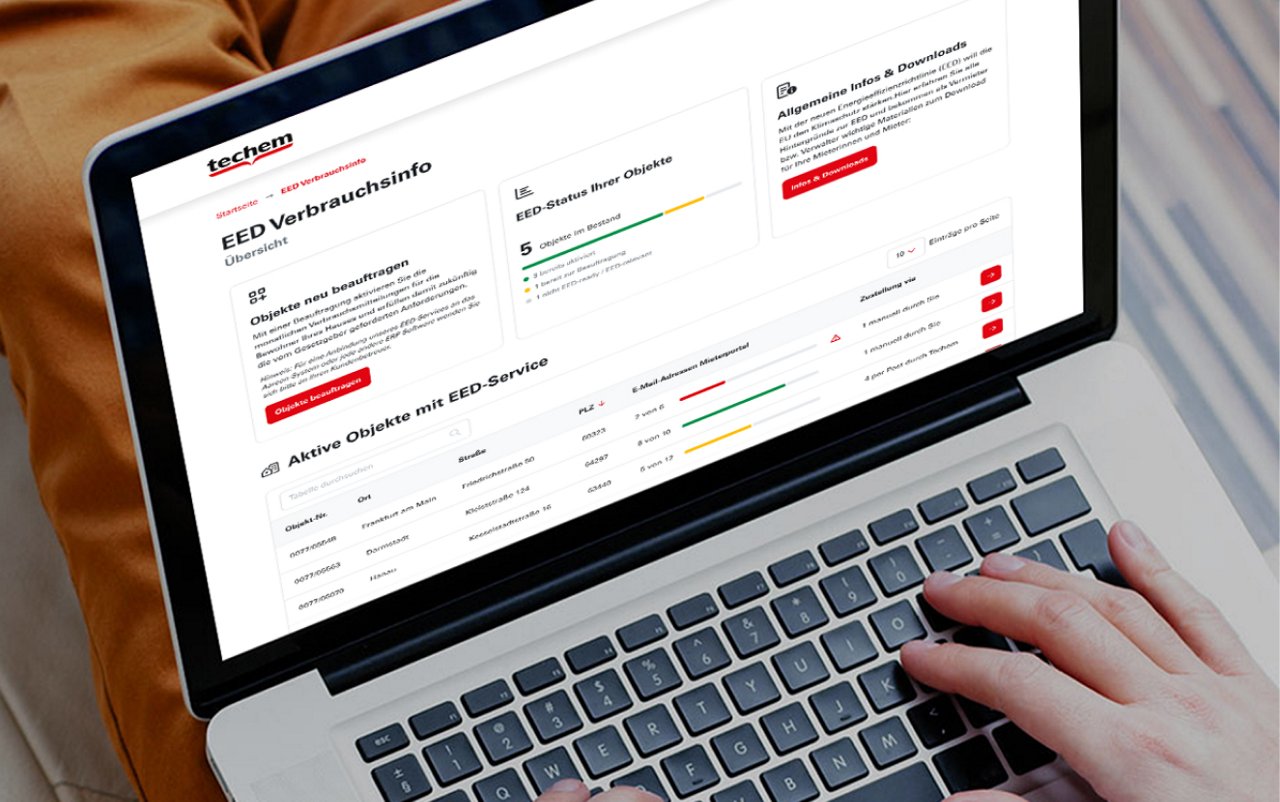 Eine Person nutzt das mein.techem Kundenportal auf einem Laptop, der auf ihrem Schoß liegt. Der Bildschirm zeigt Verbrauchsinfos, Diagramme und eine Übersicht zu aktiven Objekten mit EED-Service.