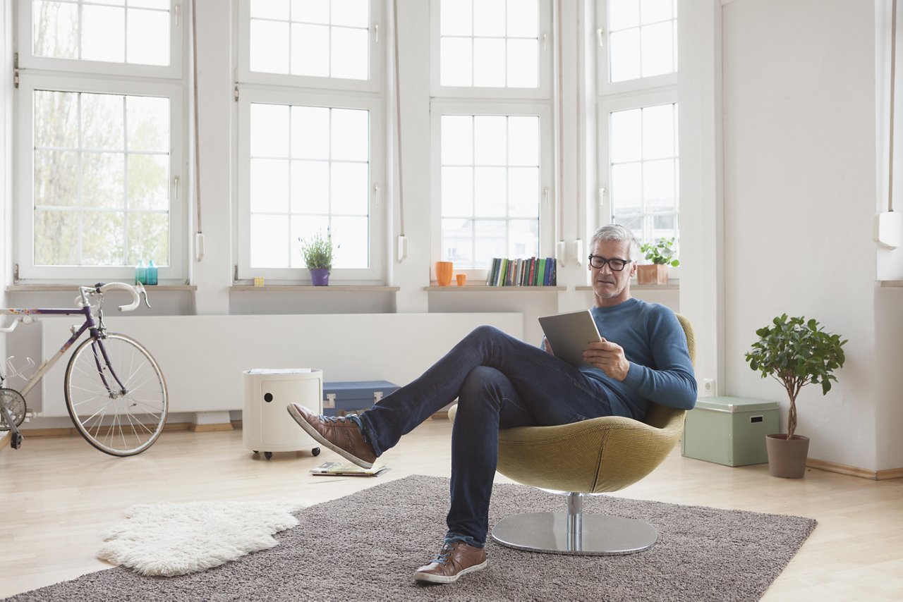 Mature man at home sitting in chair using digital tablet; Shutterstock ID 448300288; Purchase Order: -; Client/Licensee: -