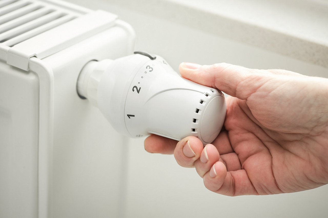 hand adjusting the temperature of heating radiator