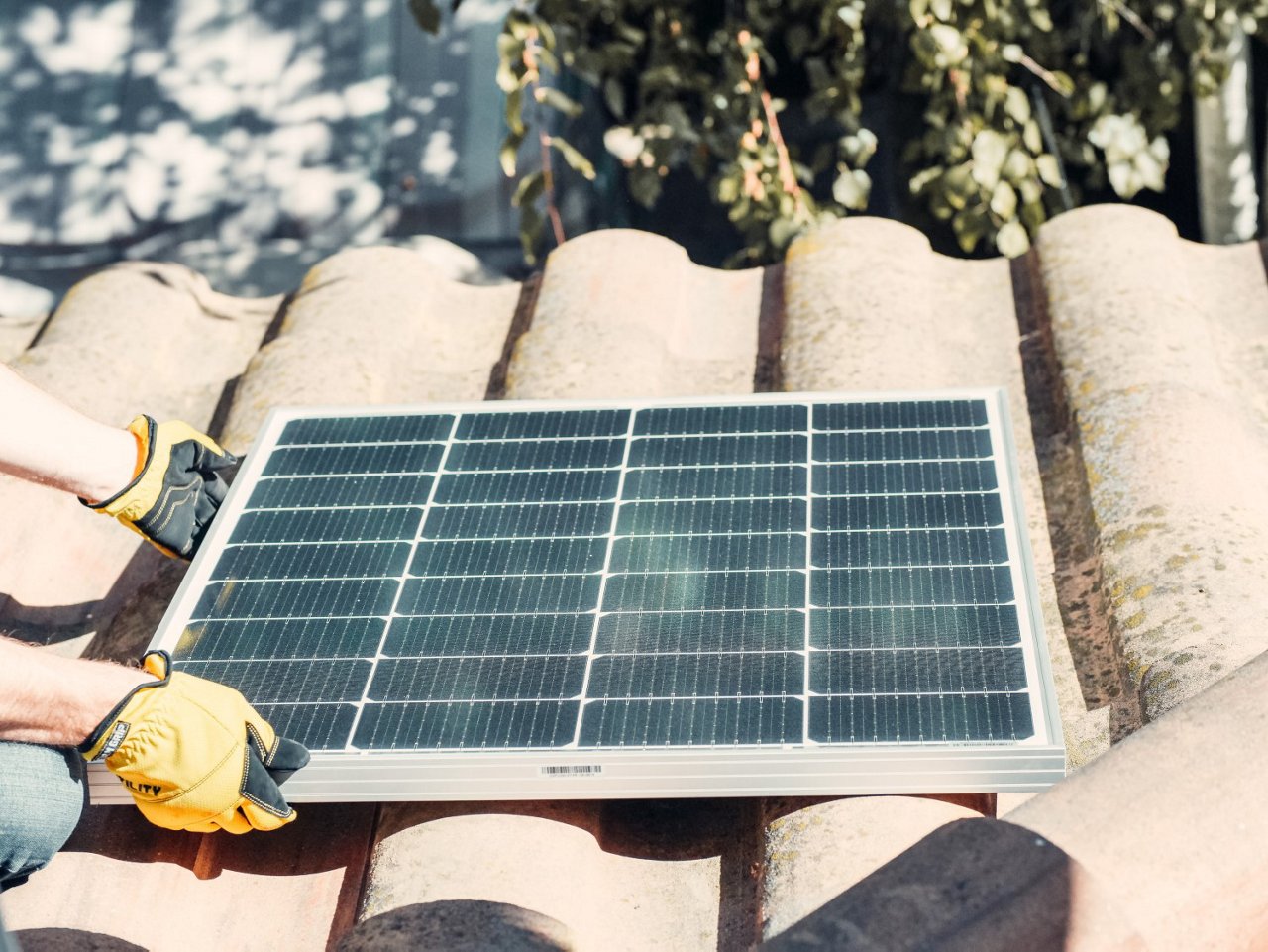 Mann montiert Photovoltaik auf Dach