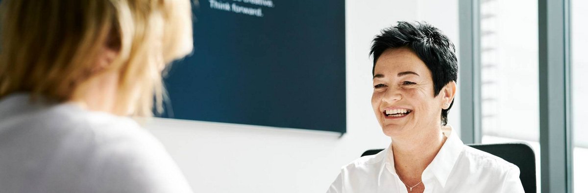 Beraterin im Gespräch mit einer Kundin in einem modernen Büro. 