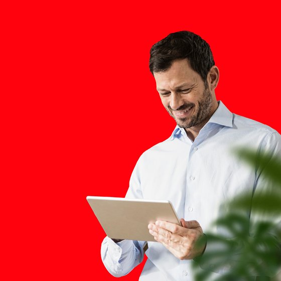 Mann mit Tablet steht vor einem roten Hintergrund