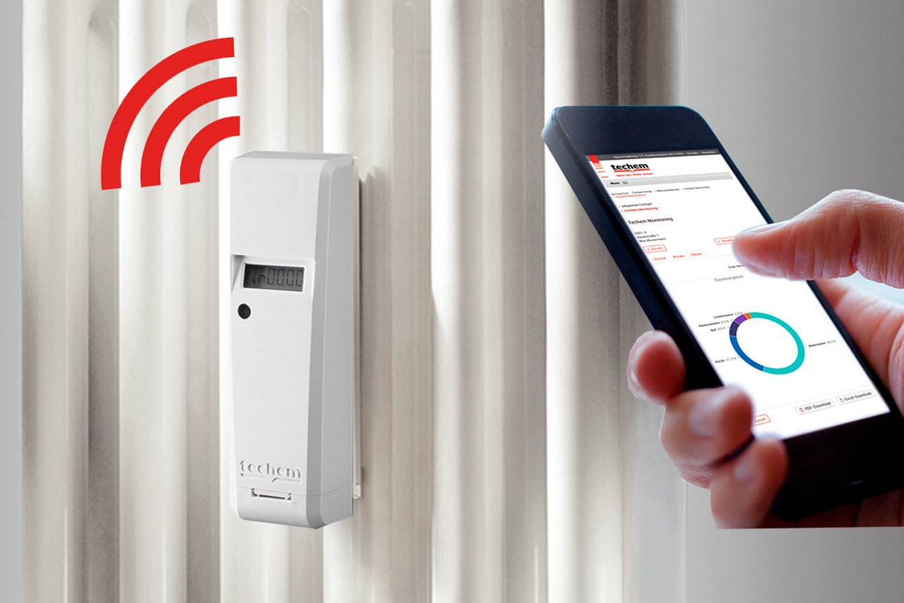 Måler på radiator med mobil, der viser data ved siden af. 