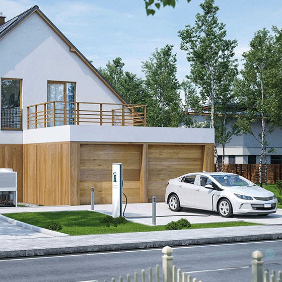 Zu sehen ist ein Einfamilienhaus mit Grünflächen. Davor steht ein Elektroauto, das gerade an einer Ladestation lädt.