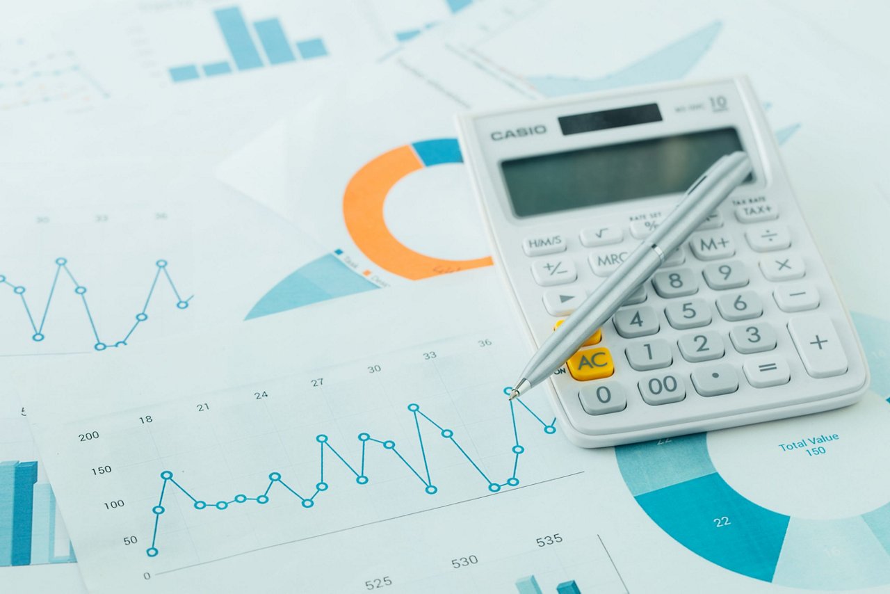 Taschenrechner und Kugelschreiber liegt auf Zetteln über Statistiken
