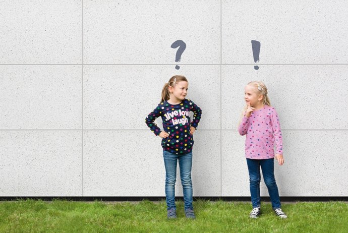 Zwei kleine Mädchen vor einer Hauswand mit einem Fragezeichen und Ausrufezeichen über den Köpfen