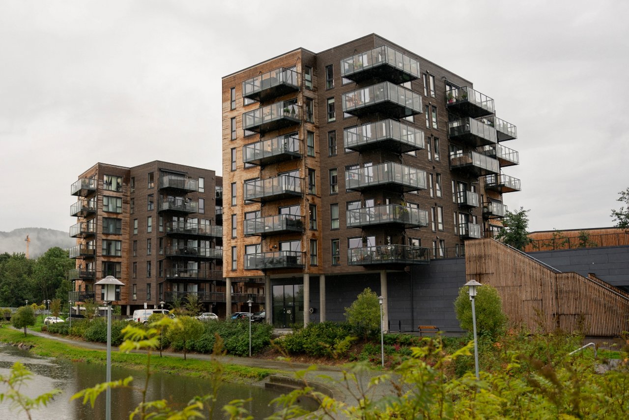 En moderne boligblokk strekker seg langs kanten av en stille elv