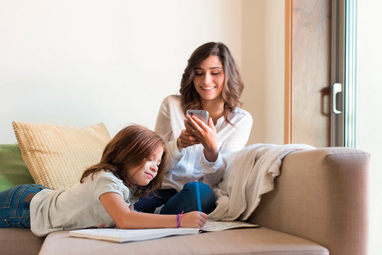 Little girl painting in the living room while mom is on internet; Shutterstock ID 393706300